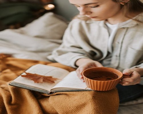 Person relaxing at home with a book and tea
